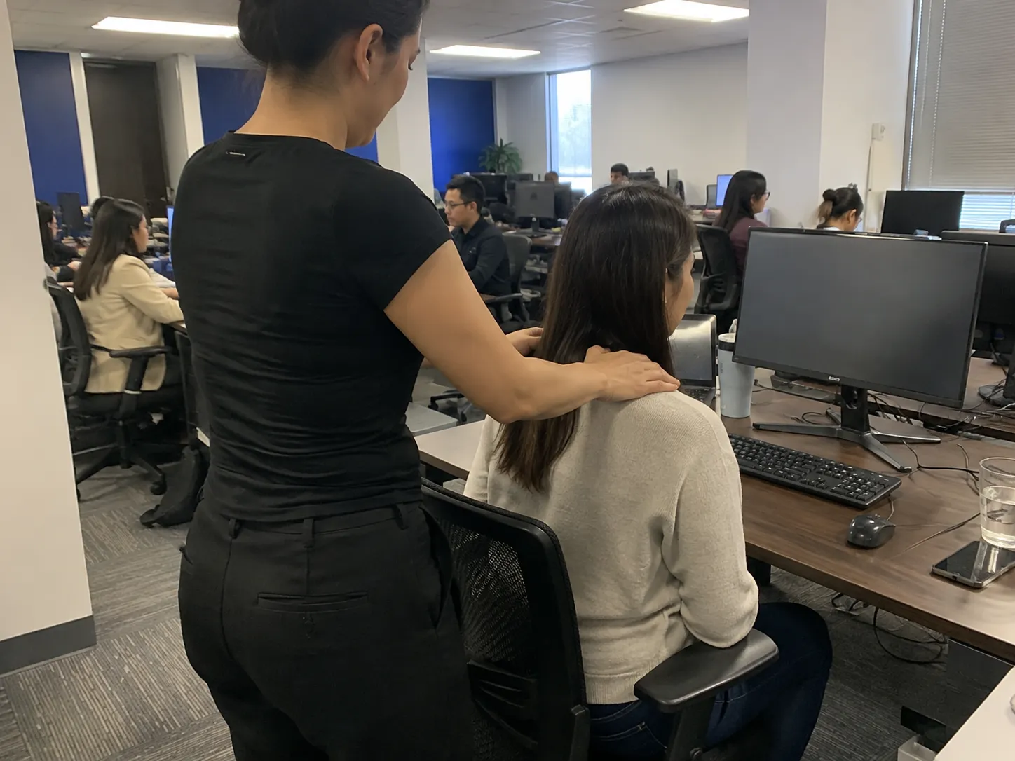 Employee receiving a brief shoulder massage at their own desk during a workplace wellness day