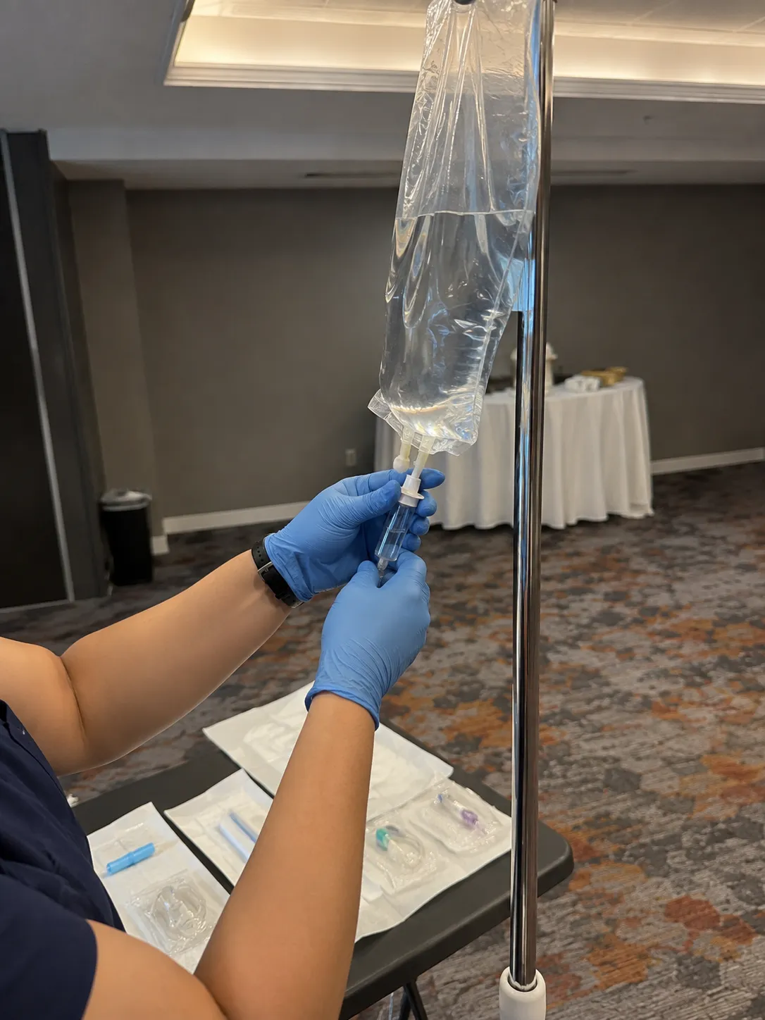 Nurse in gloves preparing an IV bag at a corporate hydration station