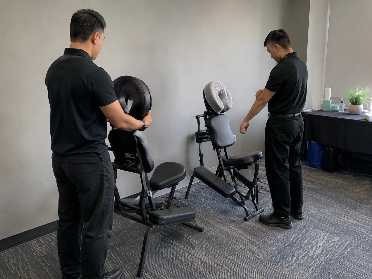 Two massage therapists preparing portable massage chairs before a corporate wellness event