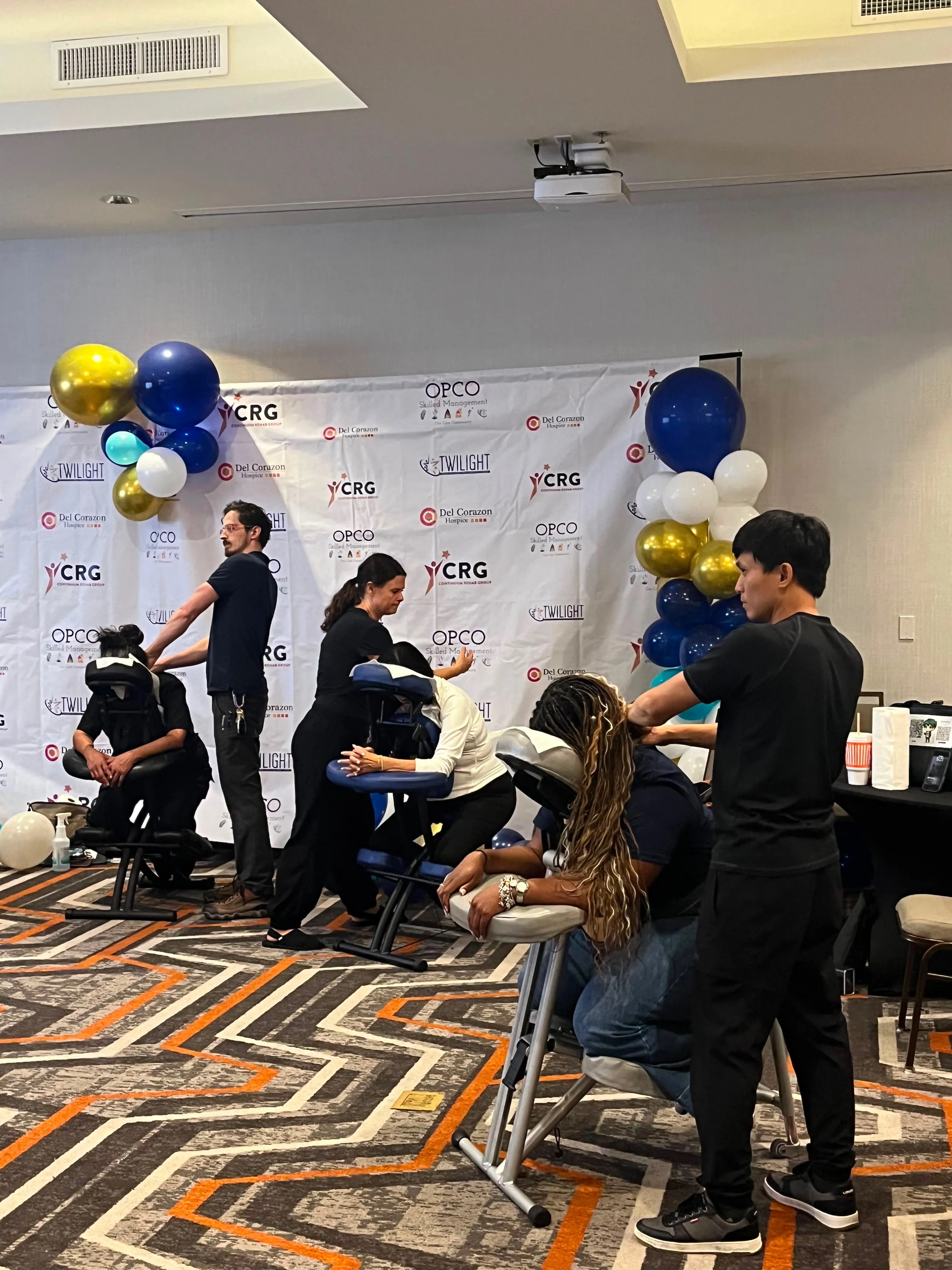 Licensed massage therapists running a chair massage rotation at a corporate wellness event